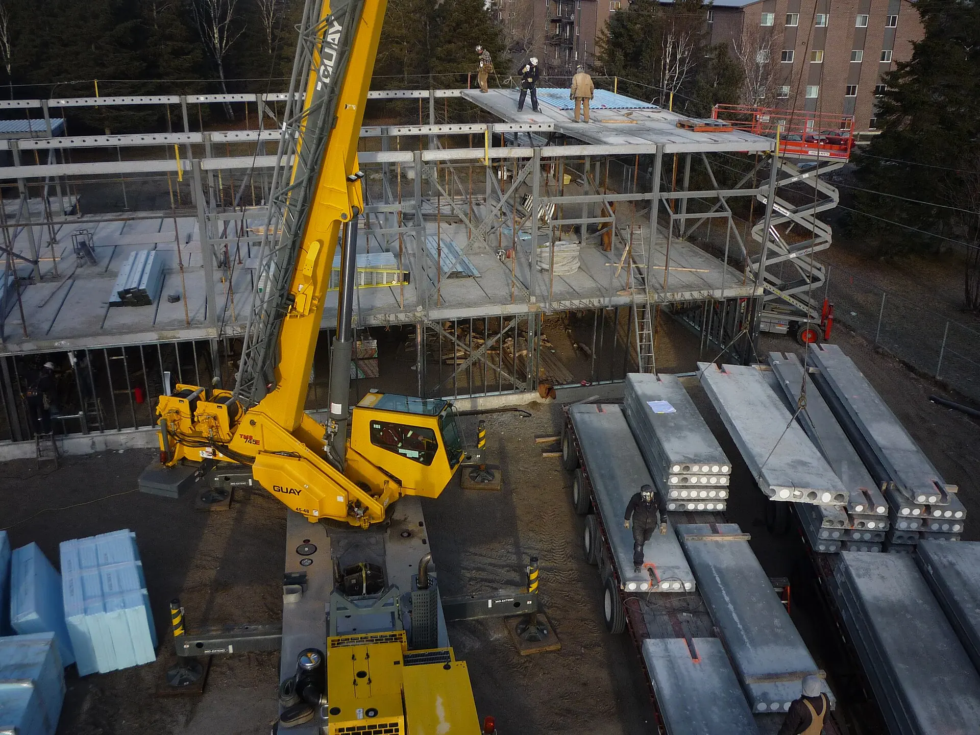 Structural steel beams staged beside a crane at a building site